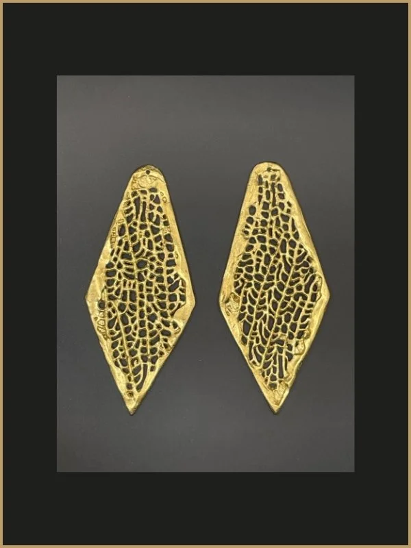 Une paire de boucles d'oreilles dorées avec un design filigrane complexe, en forme d'ovale allongé, sur un fond gris foncé.