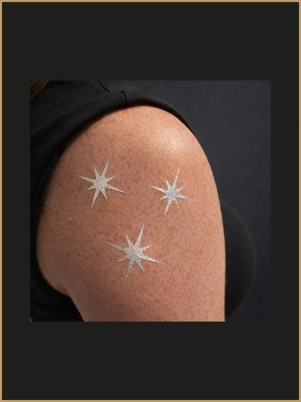 Une épaule avec des étoiles brillantes dessinées sur la peau.