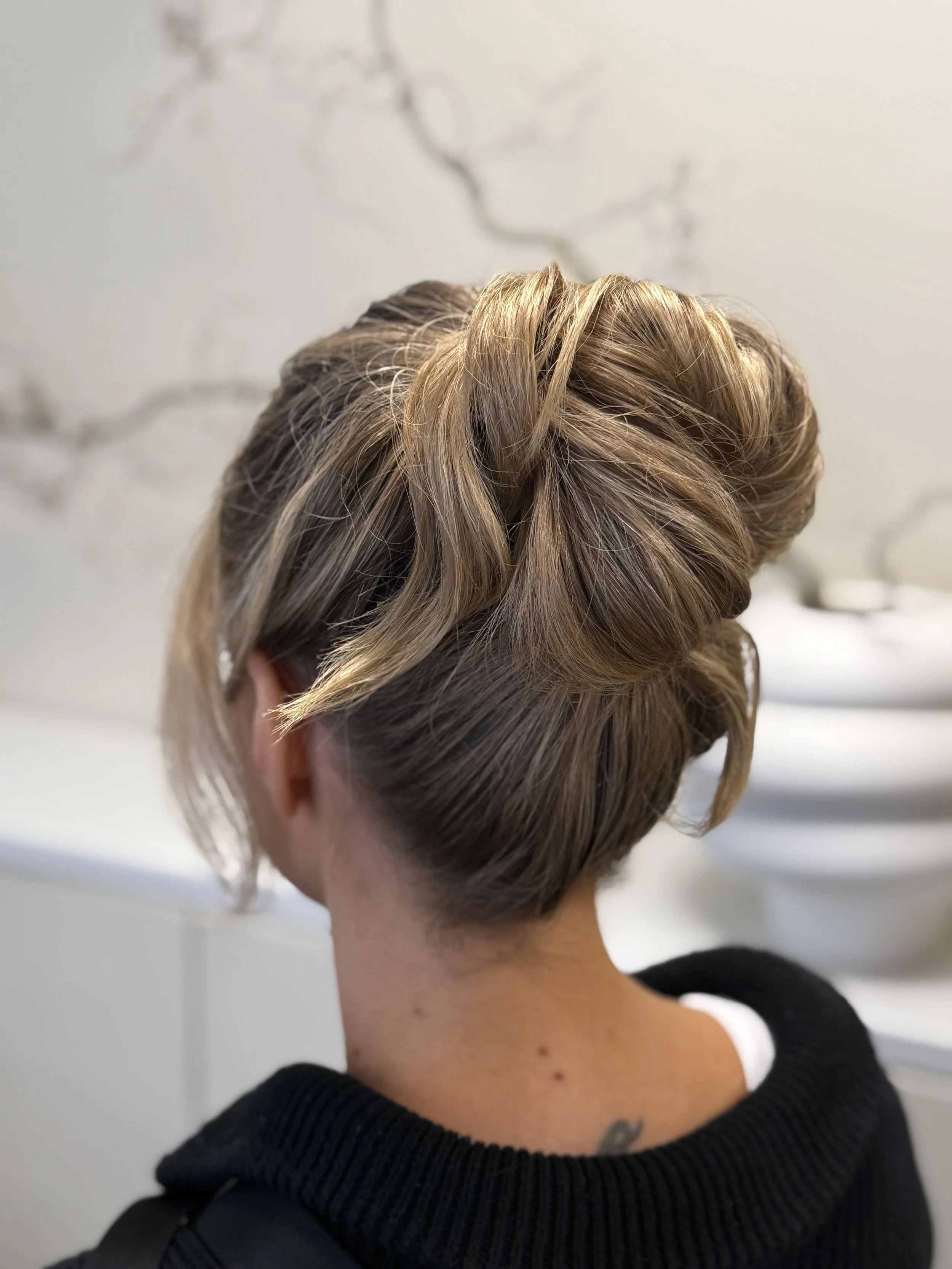 Hårklipp på person med undercut och blont lockigt hår, sedd bakifrån.