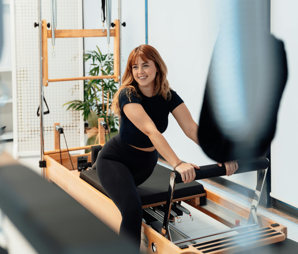 Une femme utilise un appareil de Pilates Reformer
