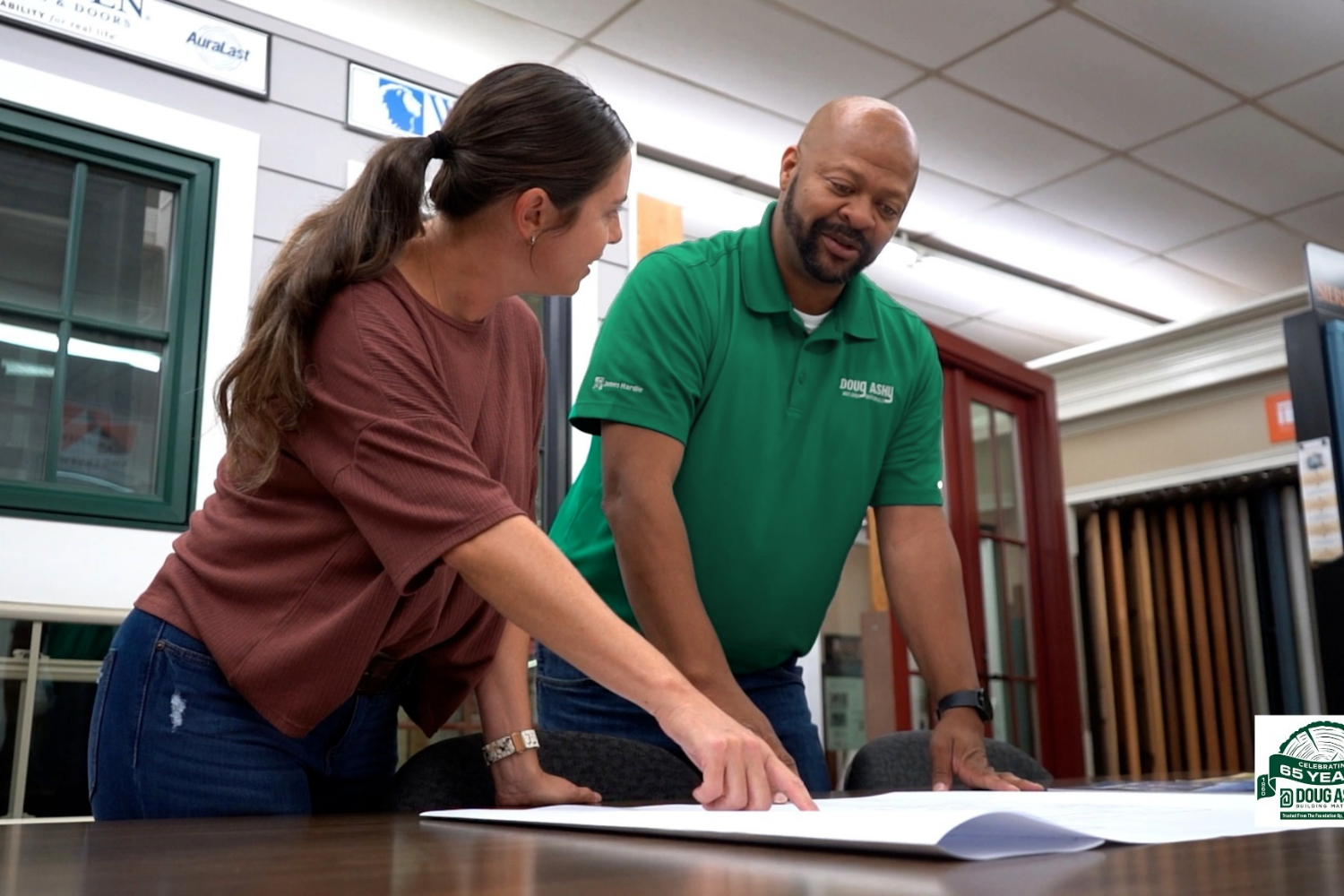 A woman looking over building plans with a Doug Ashy employee