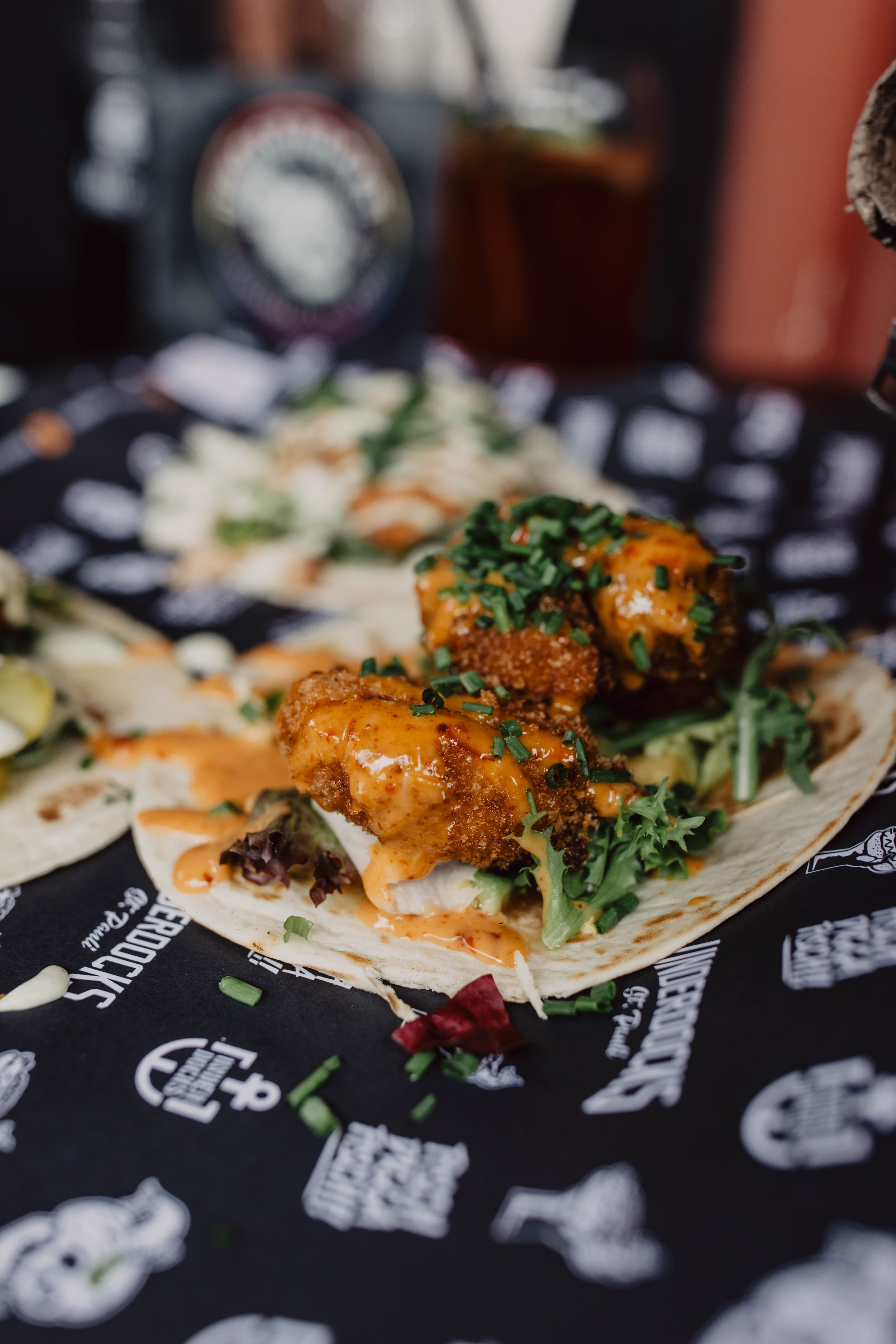 Fisch-Tacos mit Sauce und frischen Kräutern, serviert auf einer schwarzen Unterlage