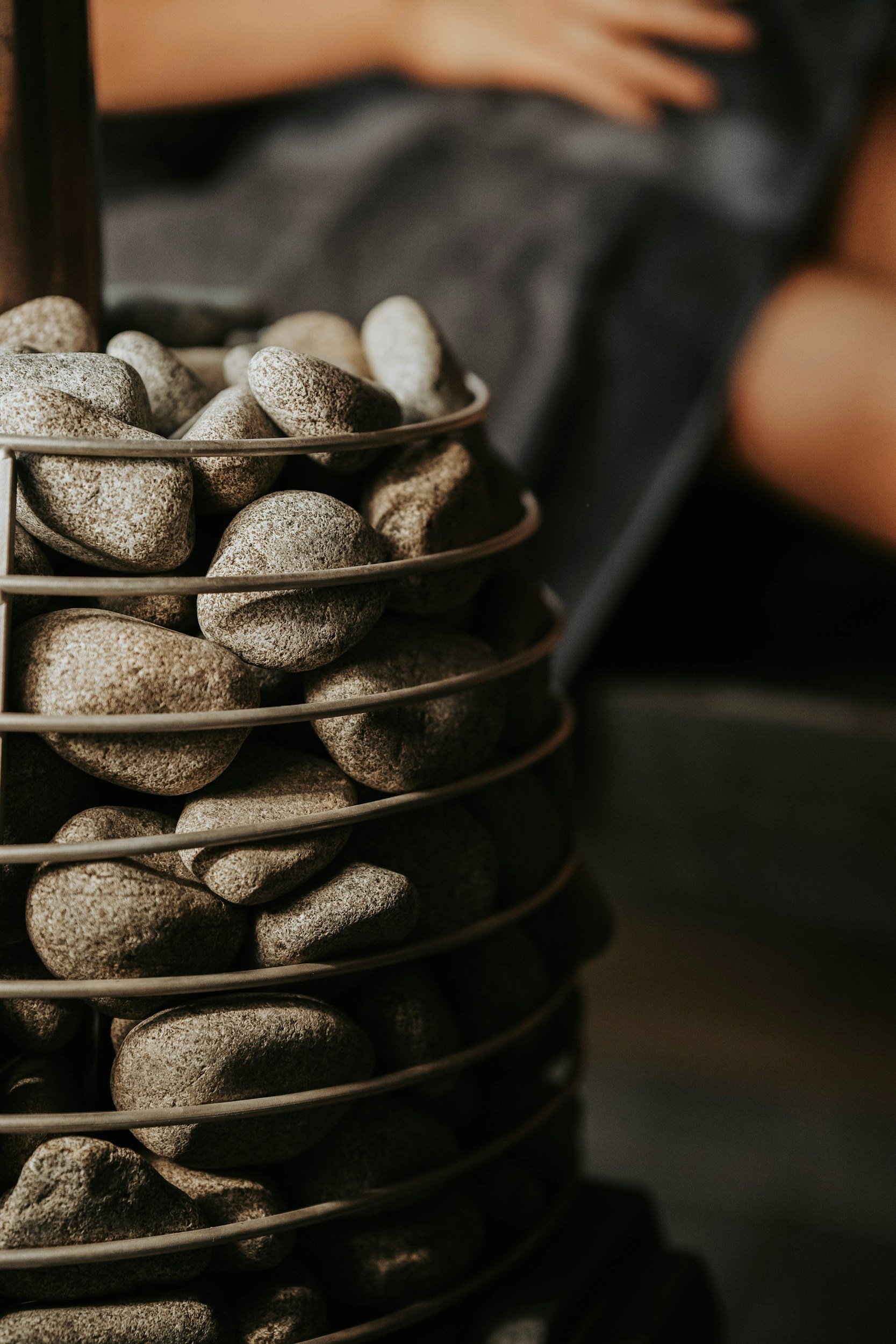 A close-up of a wire basket filled with smooth, gray river stones.