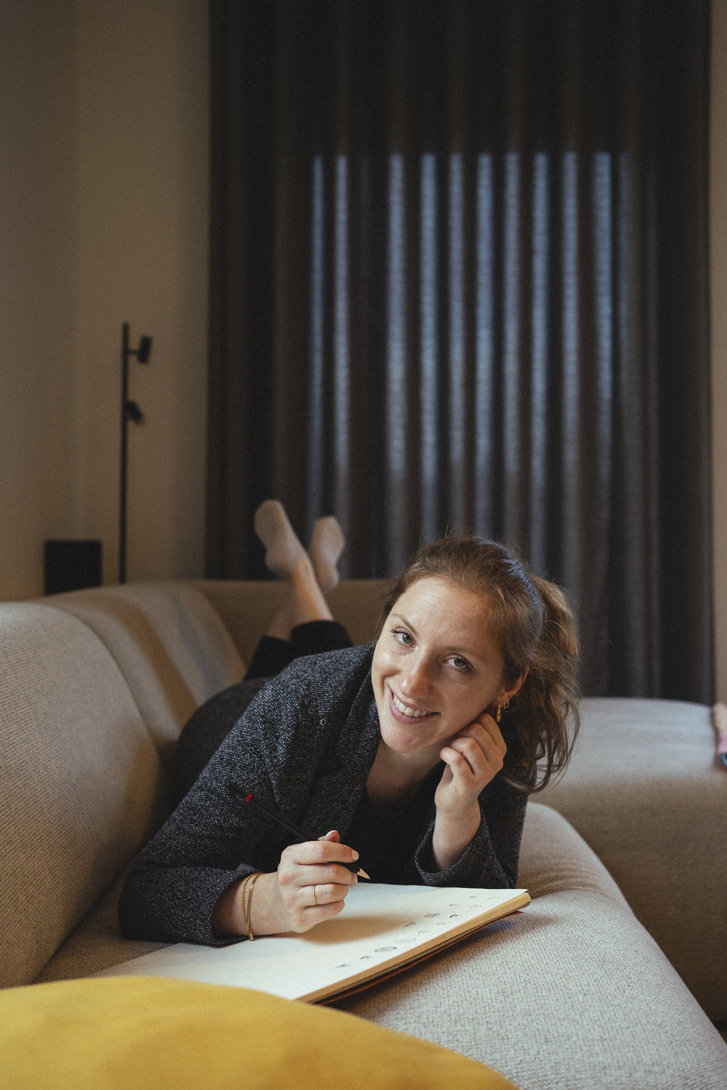 Louise kijkt op van het tekenen en lacht vriendelijk