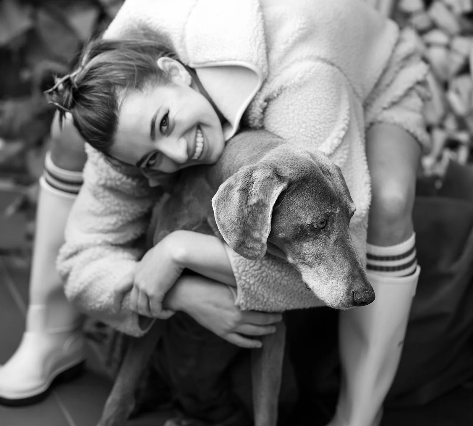 Lächelnde junge Frau, die einen Hund umarmt und viel liebe für den Hund verspürt