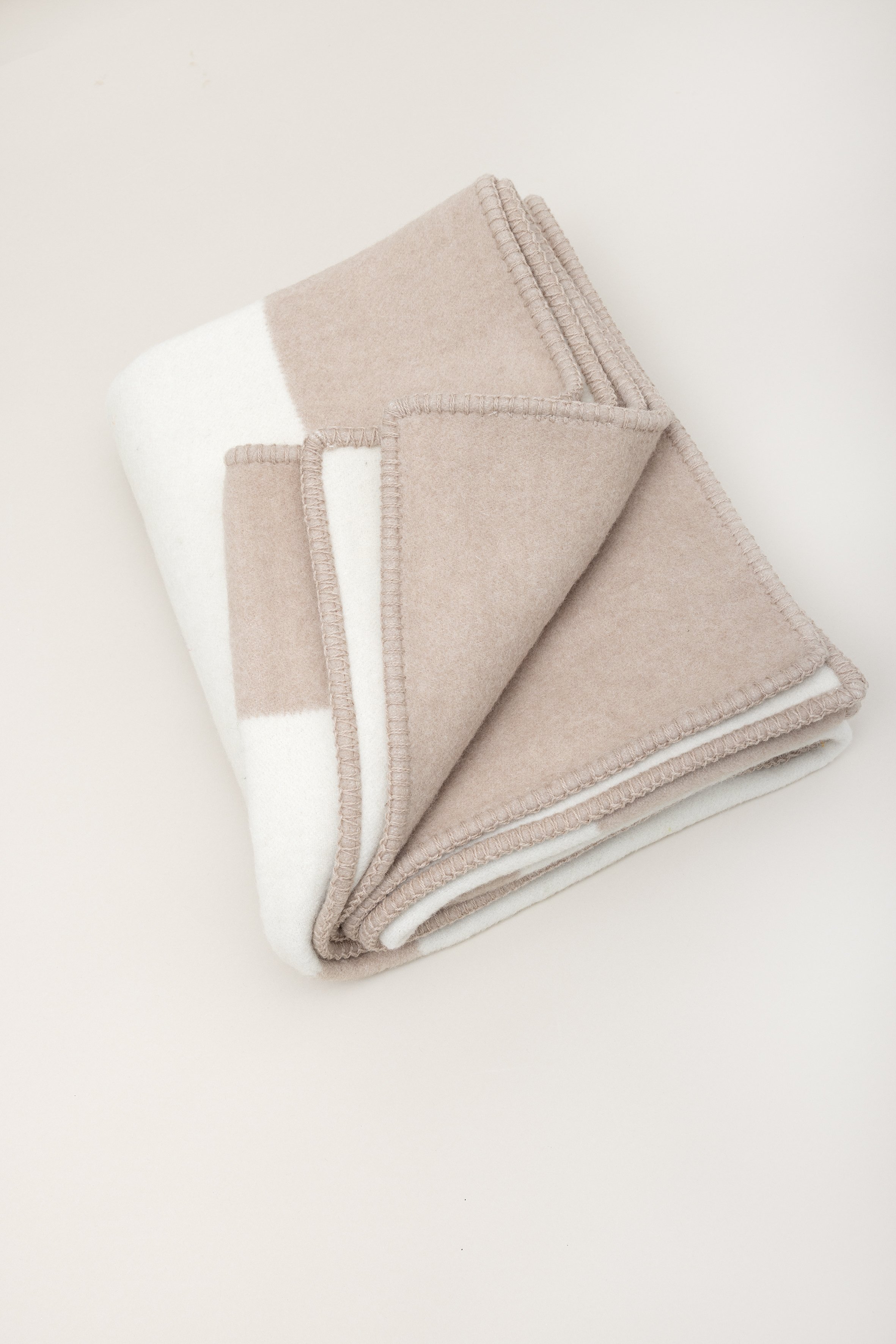 Nahaufnahme von mehreren zusammengelegten Wollsocken in neutralen Tönen auf einer weißen Oberfläche.