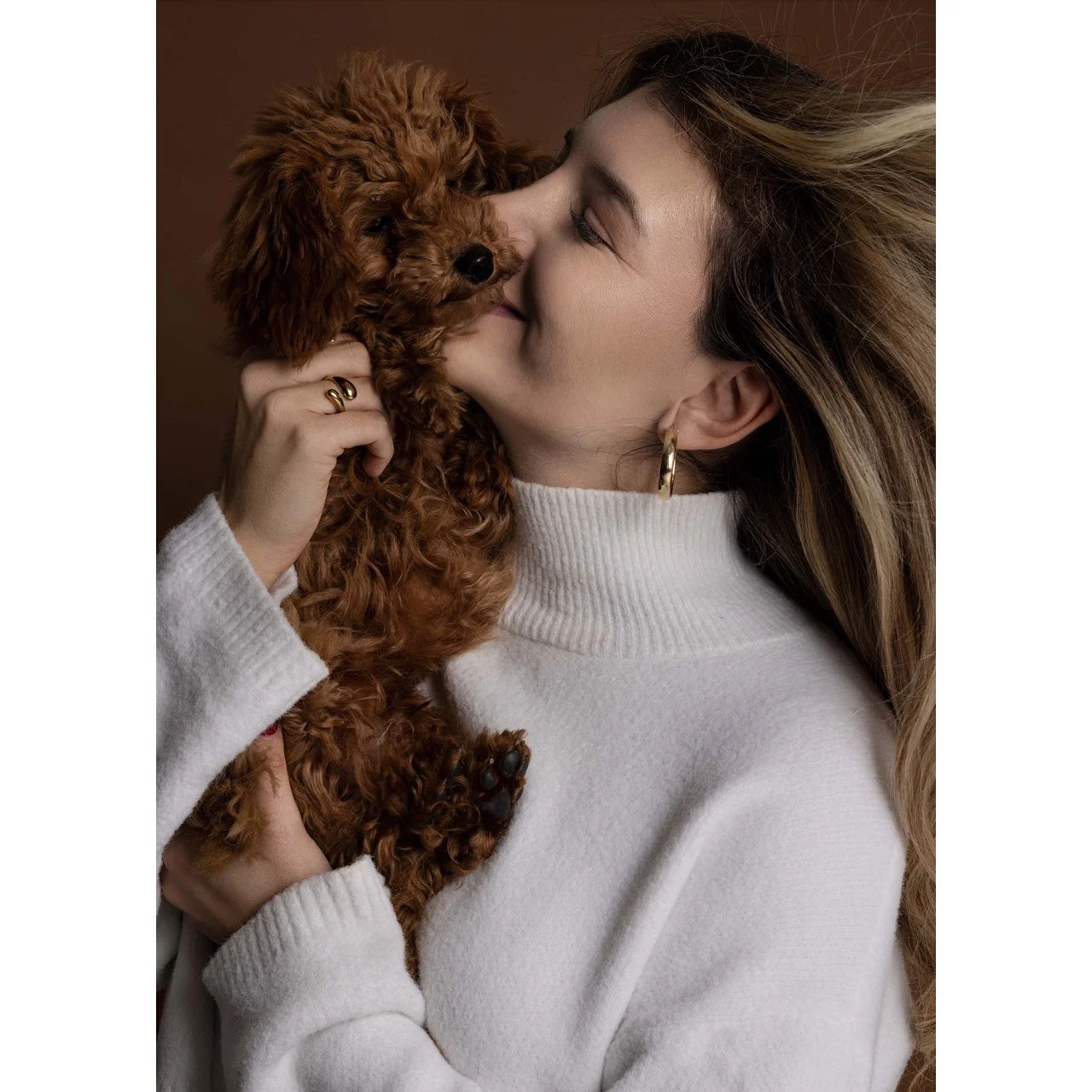 Frau kuschelt mit einem braunen, lockigen Welpen.