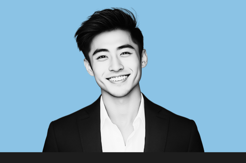 Black and white portrait of a smiling young man with dark hair, dressed in a suit with a white shirt, against a light blue background.