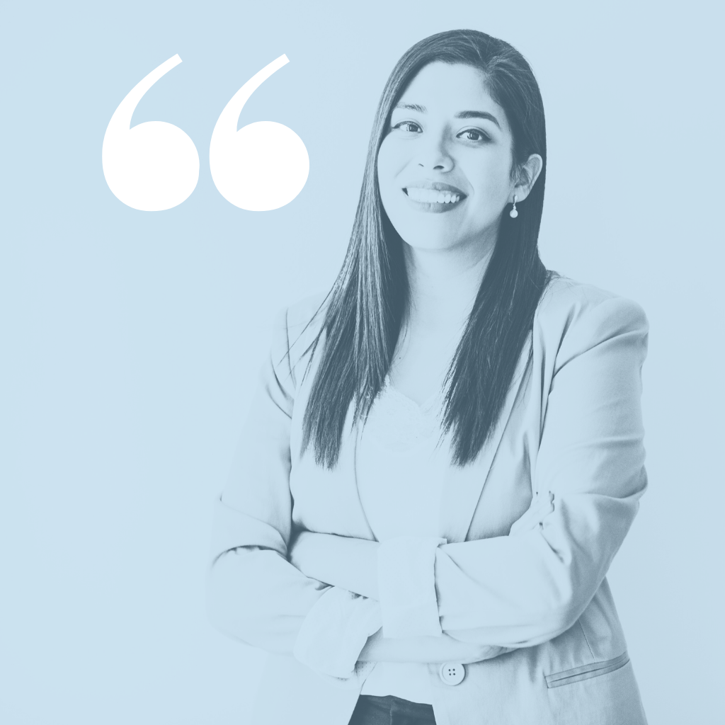 A woman with long dark hair, smiling and winking, standing with crossed arms, wearing a blazer, with a quote mark graphic in the background.