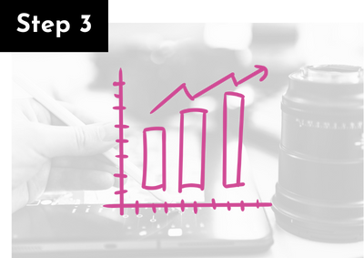 A hand holding a marker points at a black and white digital tablet displaying a pink line graph showing upward growth, with a camera lens in the background.