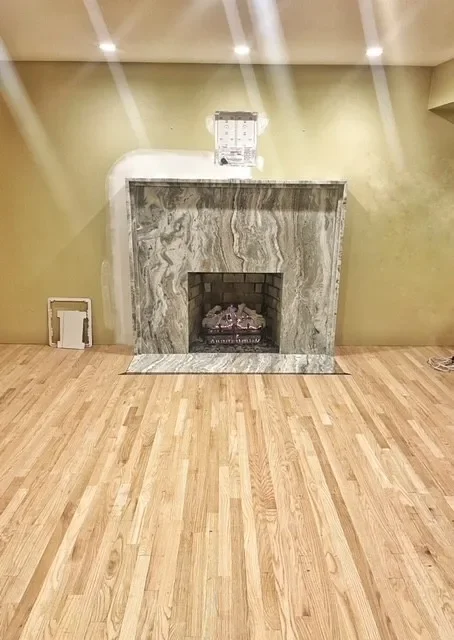 Living room with a marble fireplace on a hardwood floor, painted walls, and recessed ceiling lights.