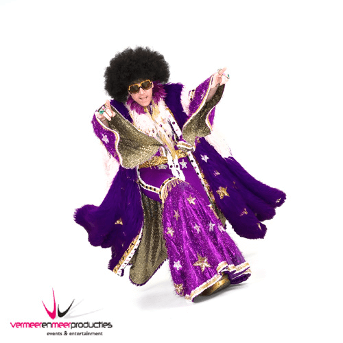 Persoon in een kleurrijk kostuum met grote bril, periodes en een afro-haar, dansend en poseren.