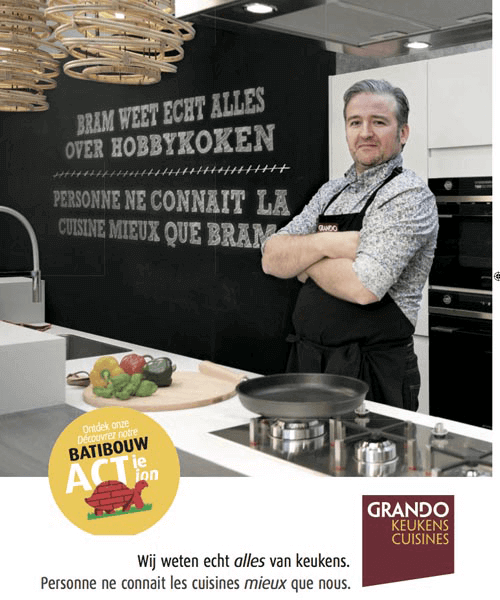 Man in een keuken met een zwart uniform en een muur met tekst in het Nederlands.