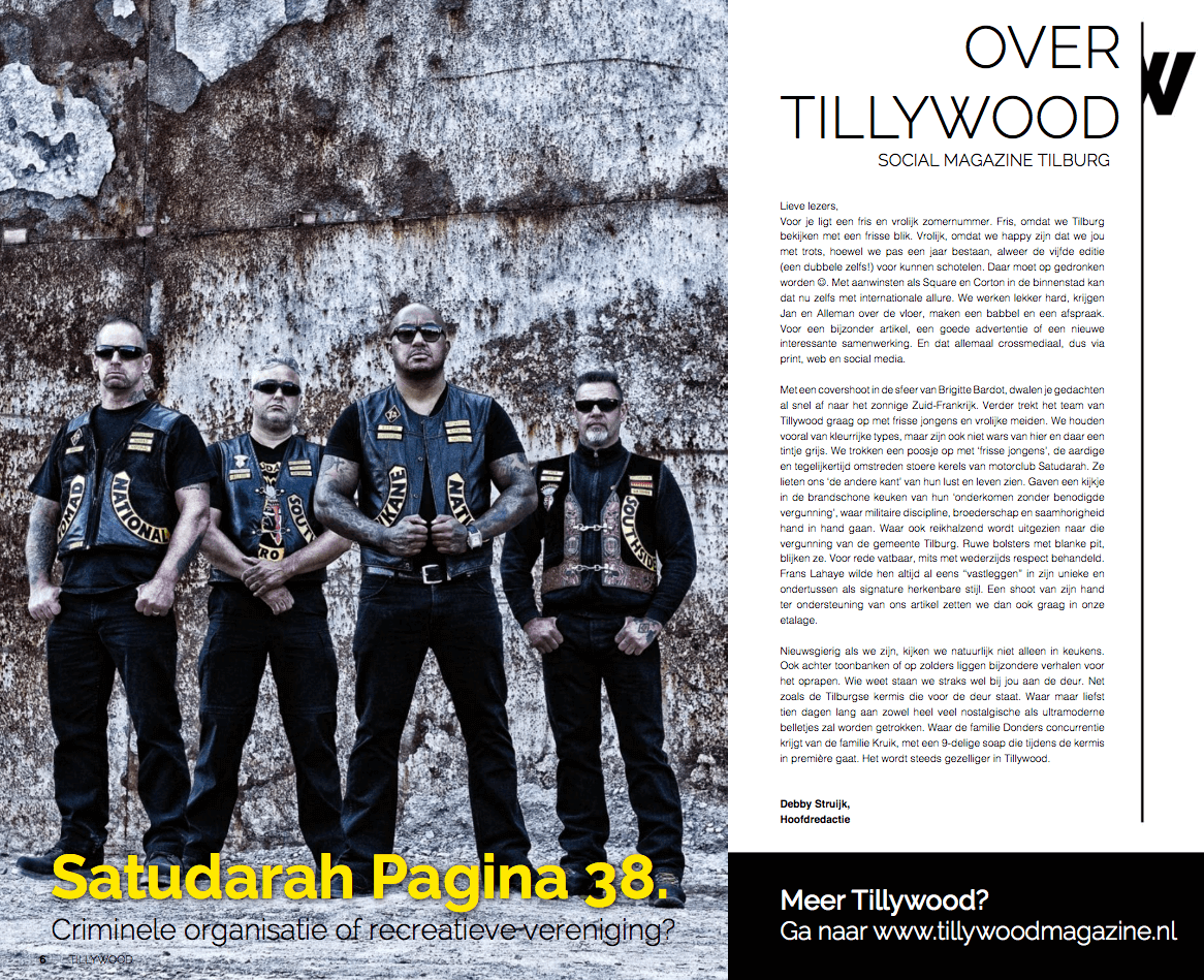 Een groep van vier mannen in zwarte kleding en zonnebrillen staan voor een oude, vervallen muur. Ze dragen vesten met patches en tekst zoals 'NATIONAL', 'SA', en 'RO'.