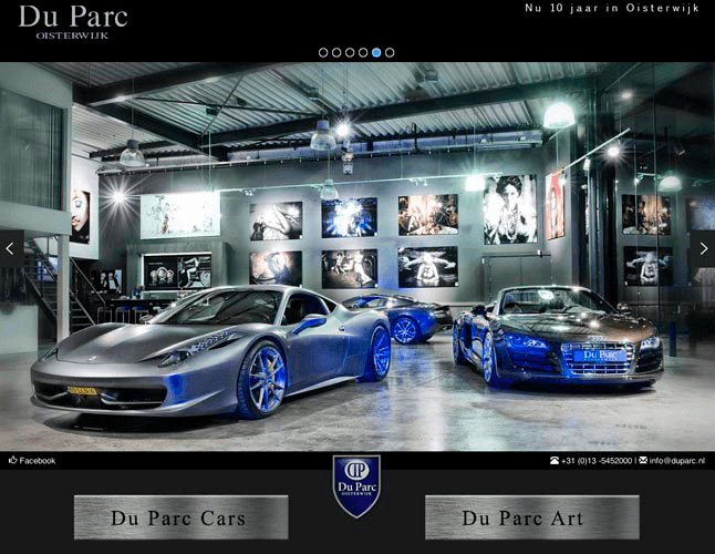 Drie luxe sportauto's in een autodealer of tentoonstelling, met kunstfoto's aan de muur en industriële verlichting.