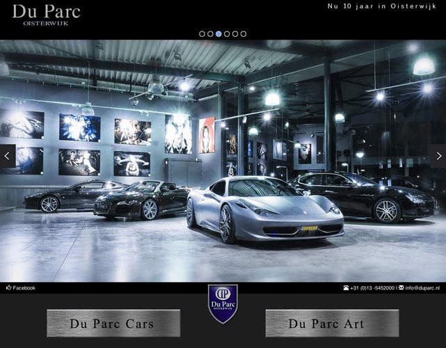 Interieur van een carrosseriewerkplaats met meerdere luxueuze sportauto's, verlichte kunstwerken aan de muur en een moderne uitstraling.