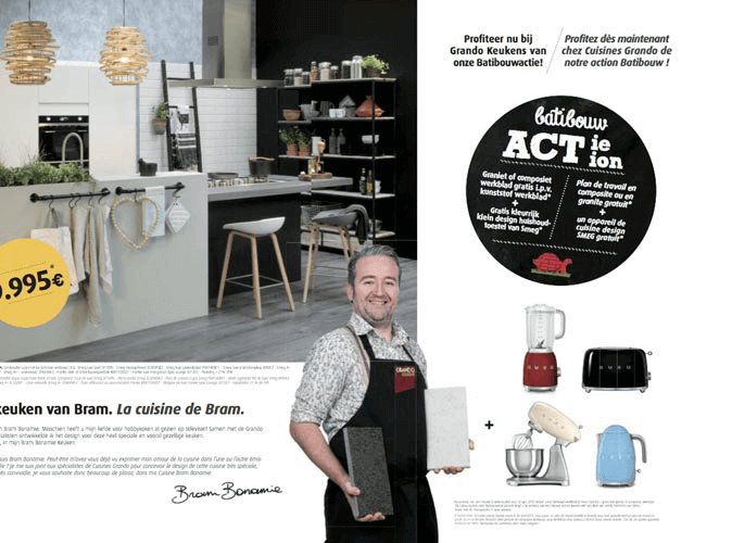 Een man lachend in een keukenwinkel met keukengerei en apparaten op de achtergrond, inclusief een blender, broodrooster, en koffiemolen.