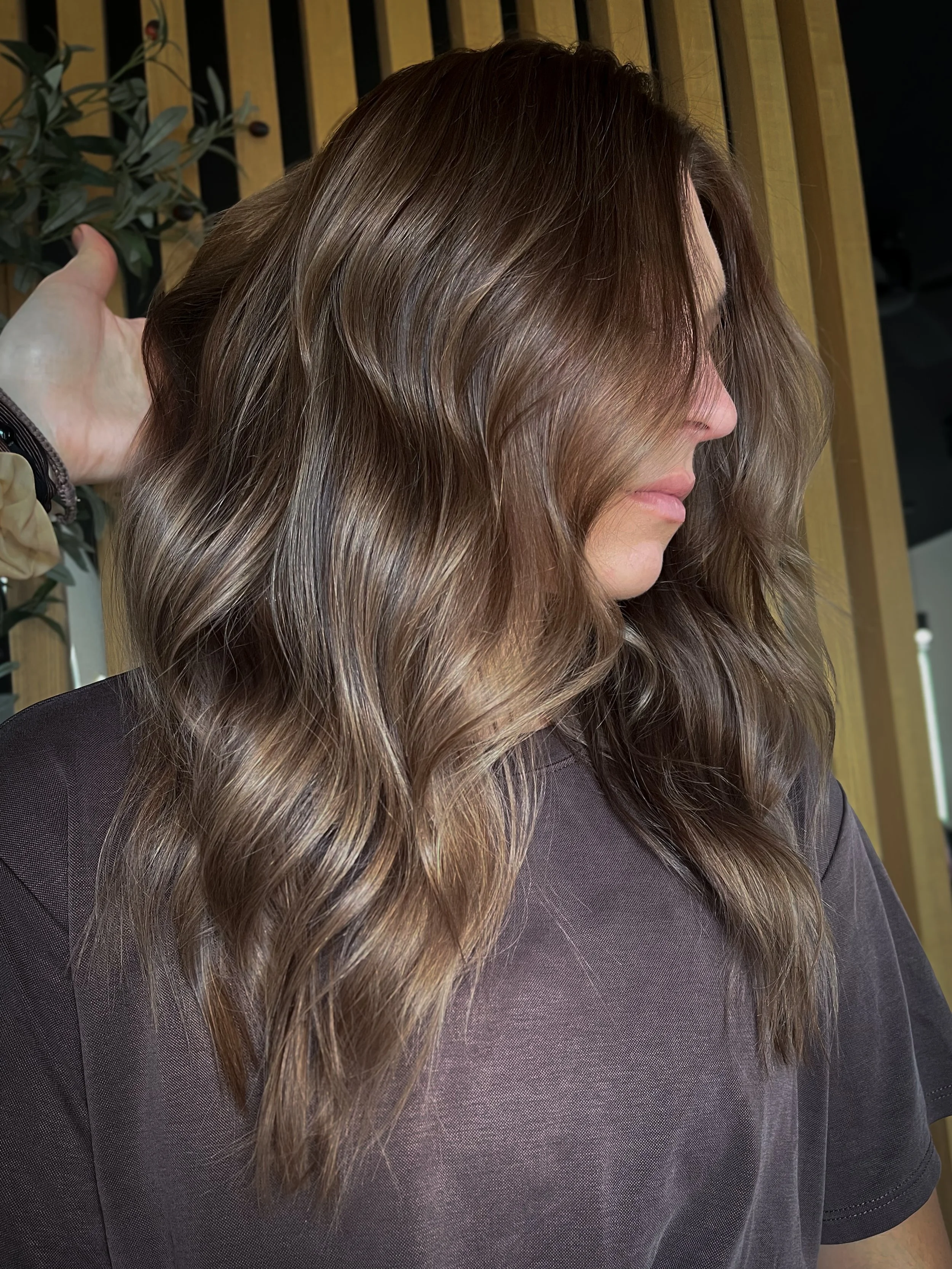 Young women with brunette hair posing to show off her subtle highlights. The color is a lived-in style color technique. 