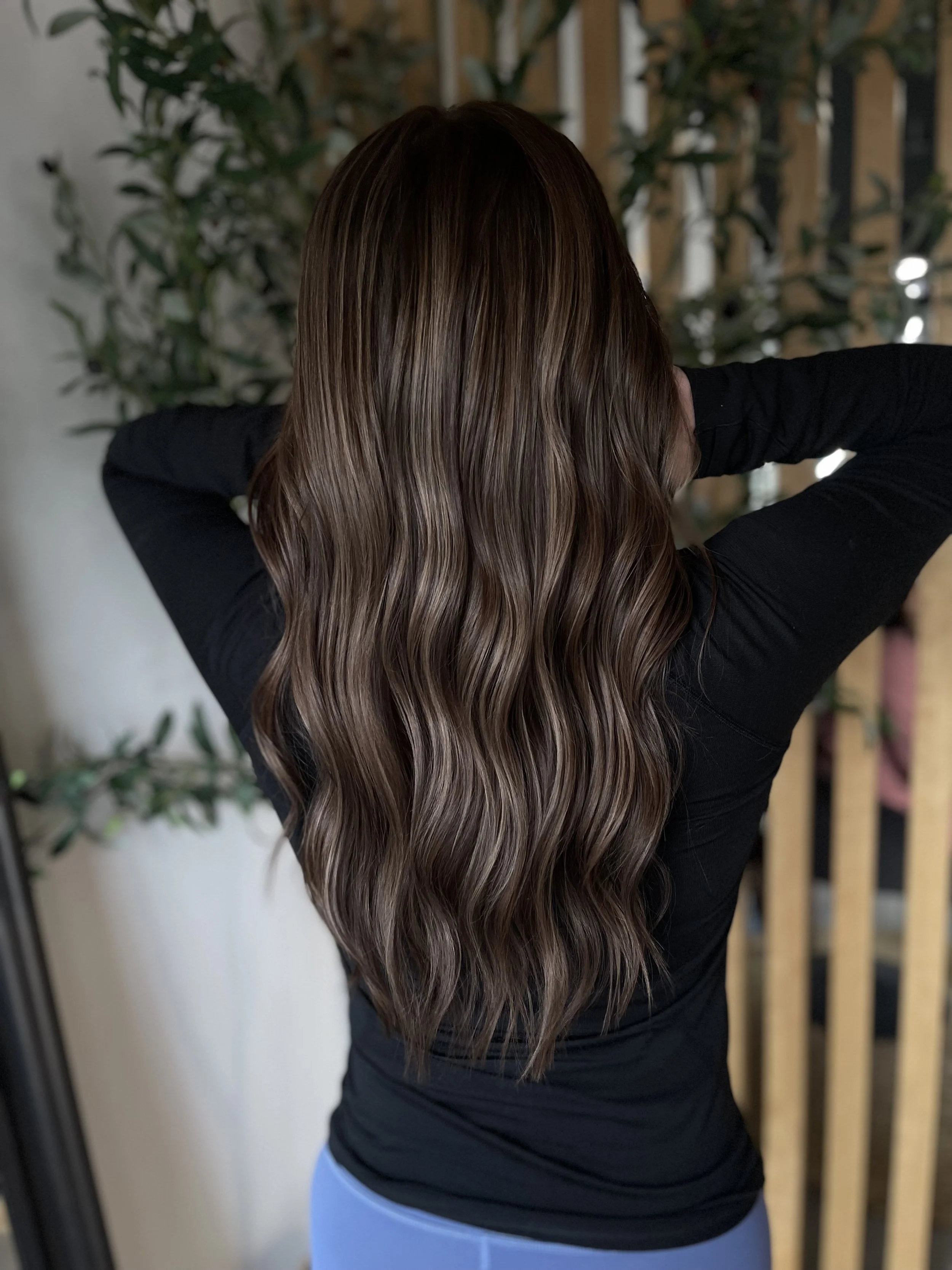 A young woman posing while showing off her brunette hair with subtle highlights.
