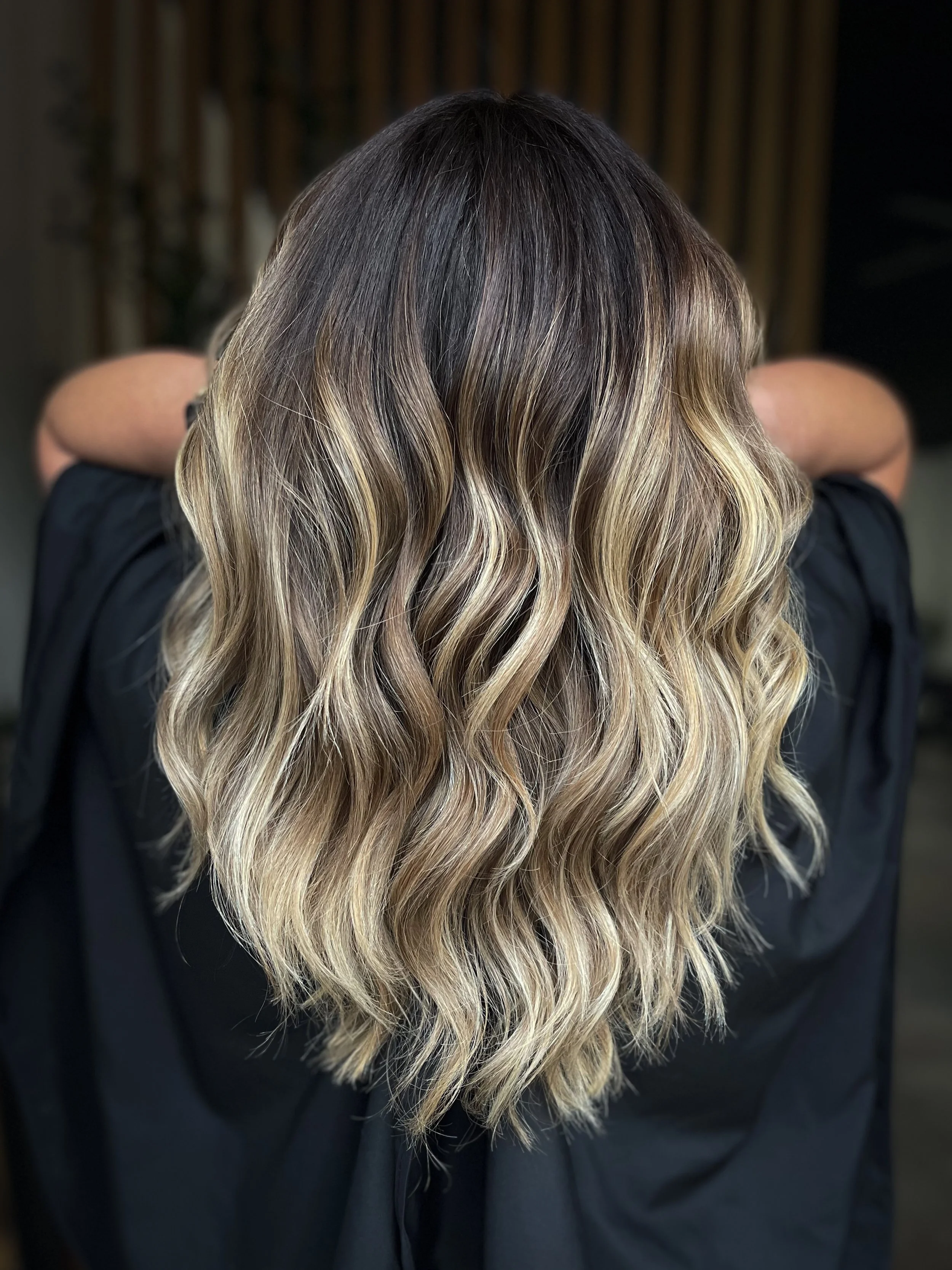 A woman posing while showing off her brunette to blonde balayage.