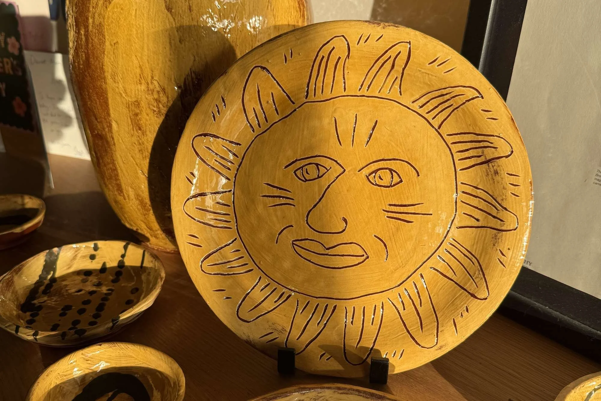 Decorative plate with a hand-drawn sun face design featuring a smiling face and sun rays, illuminated from behind.