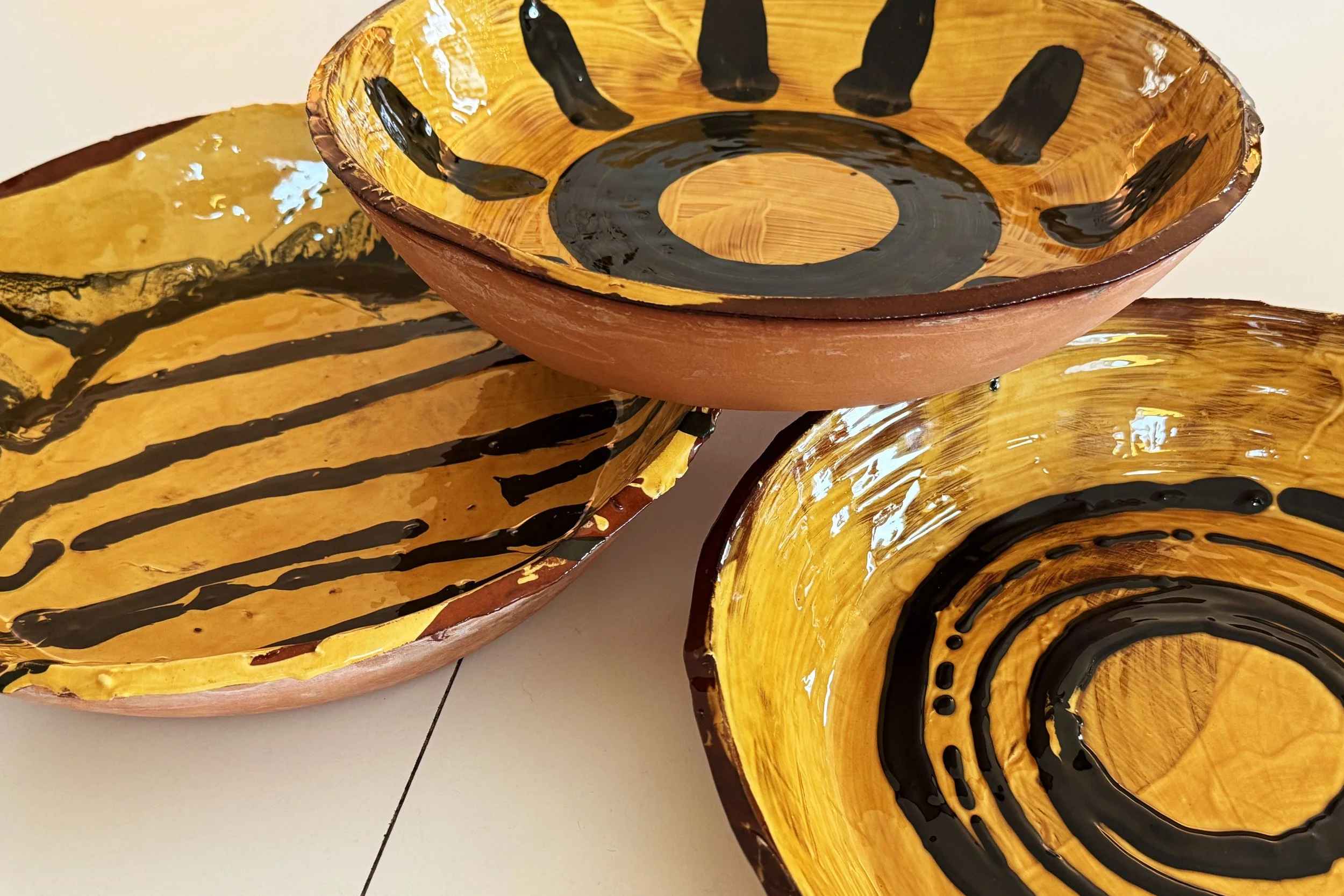 Decorating is fun, whether small or large like these serving bowls. Slabs of grogged terracotta laid into a large wooden mould, slip decorated with while and black slip then then left to gently dry and bisque fire before the honey glaze. 32cm diamete
