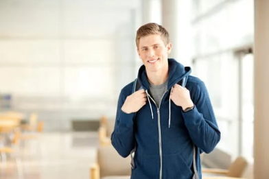 Young man with backpack smiling in a bright indoor space