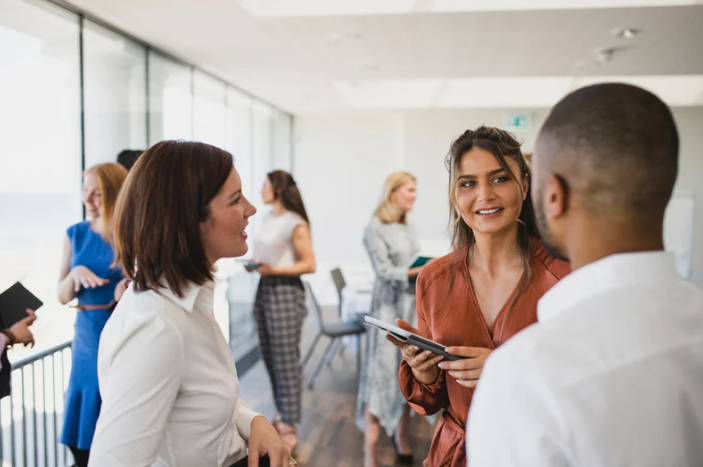 A group of smiling individuals at a networking session talking with each other