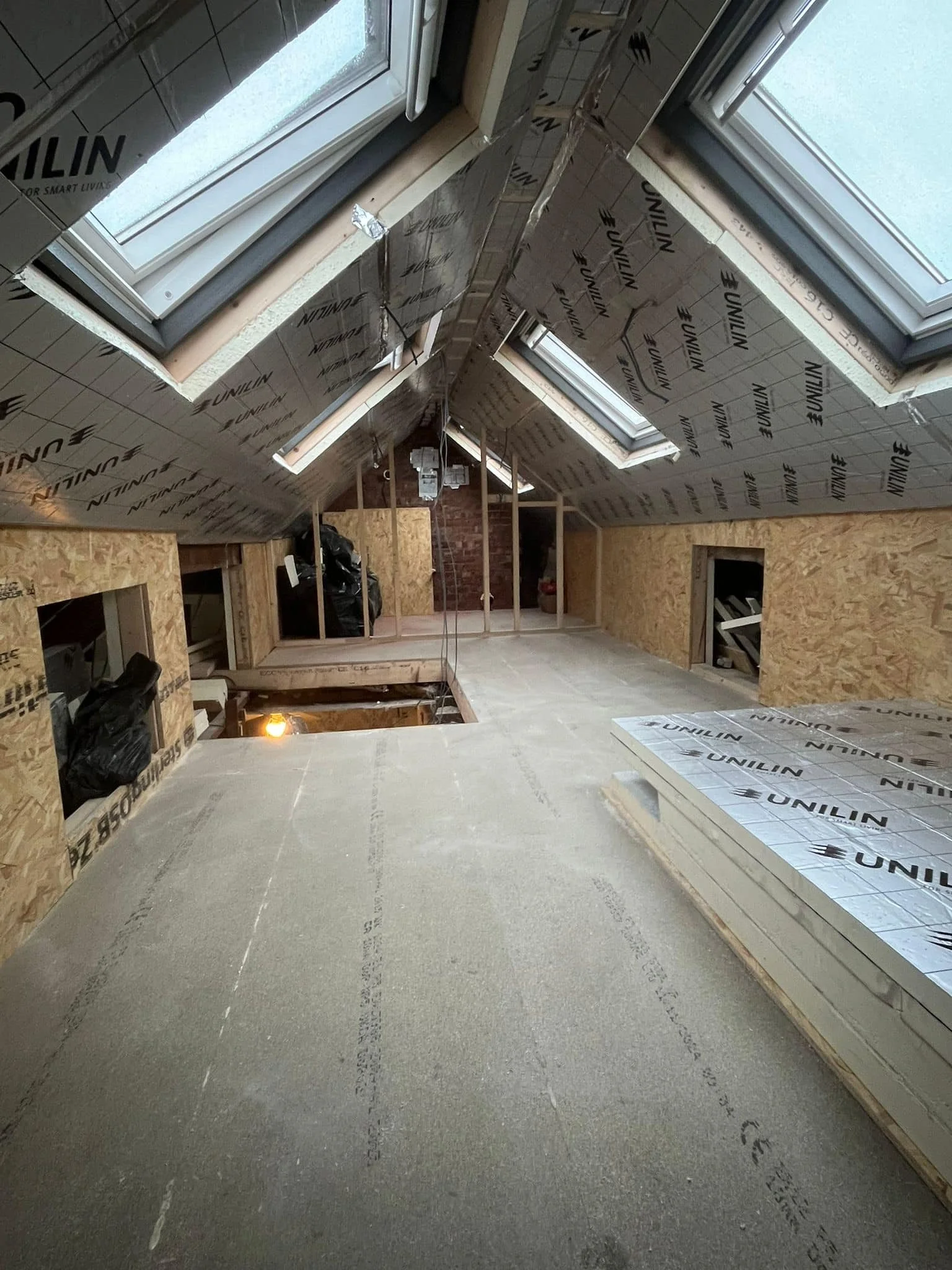 Attic under construction with roof insulation, skylights, and unfinished walls.