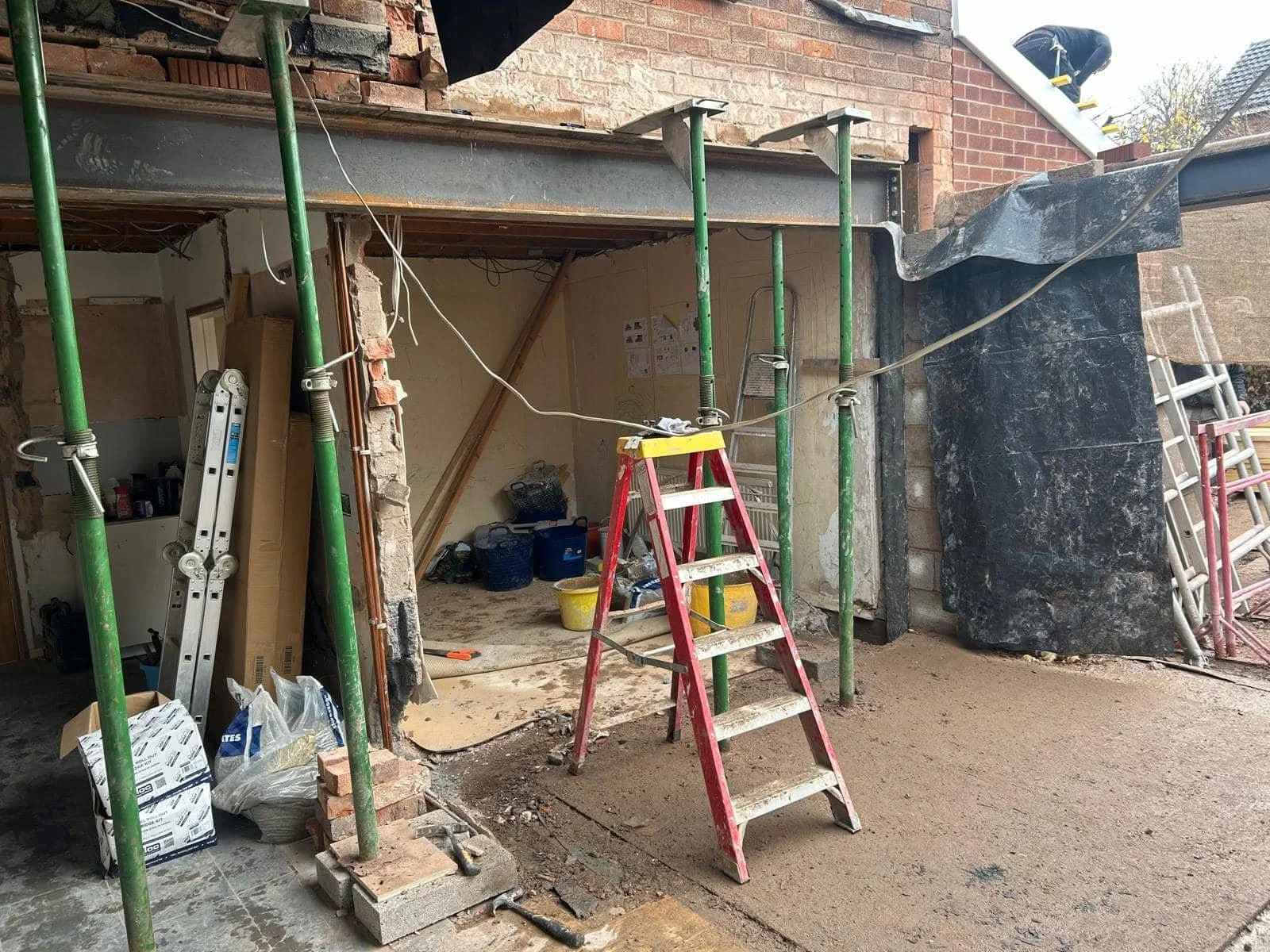 Construction site with scaffolding, ladders, and building materials for renovation or remodeling of a building.