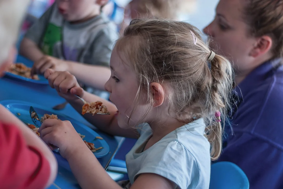 A young girl enjoying a tasty, balanced meal with her friends at Little Shipmates Day Nursery