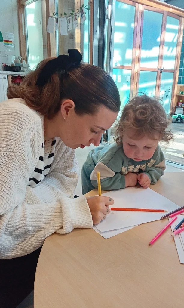 Parent and child drawing together during a nursery parent day creative activity at a table