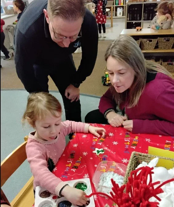 A young girl making a picture with her parents during a family day.