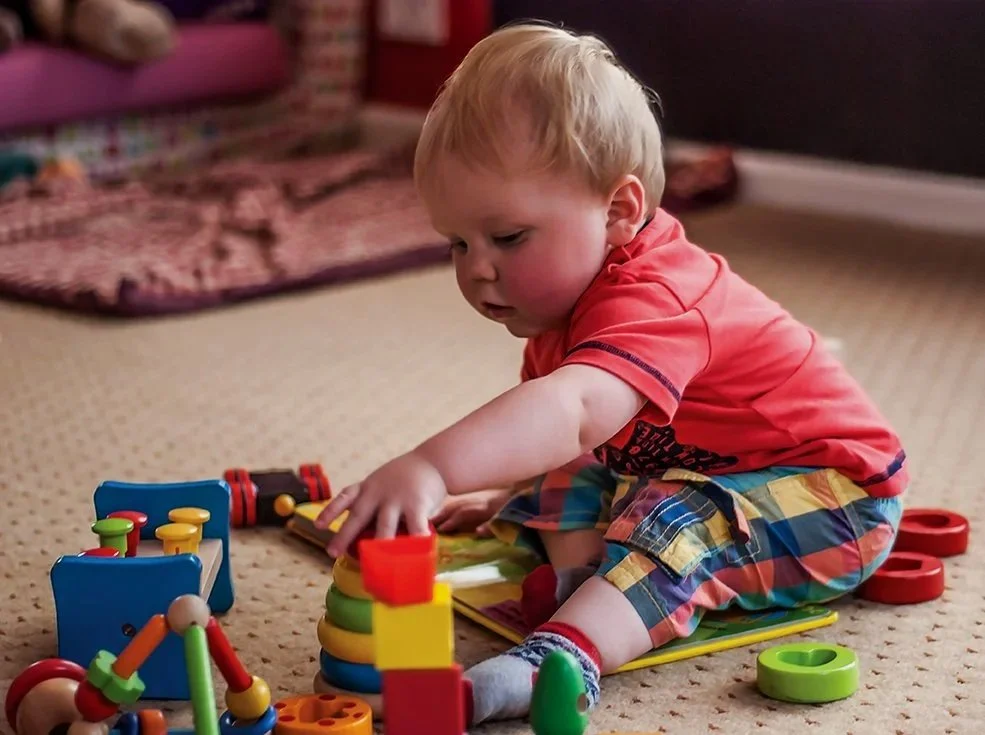 A young child reaching for some building blocks