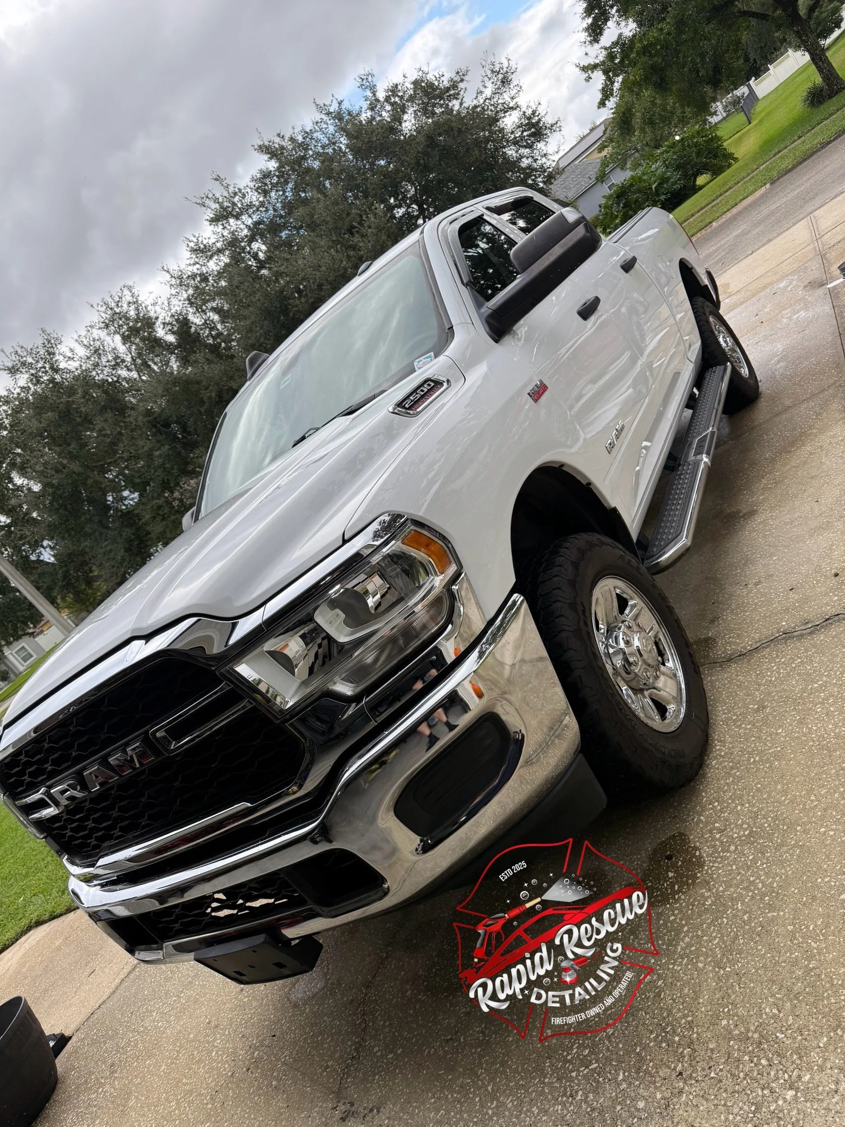 White RAM pickup truck parked on driveway with trees and houses in the background. The image has a "Rapid Rescue Detailing" logo overlay at the bottom.