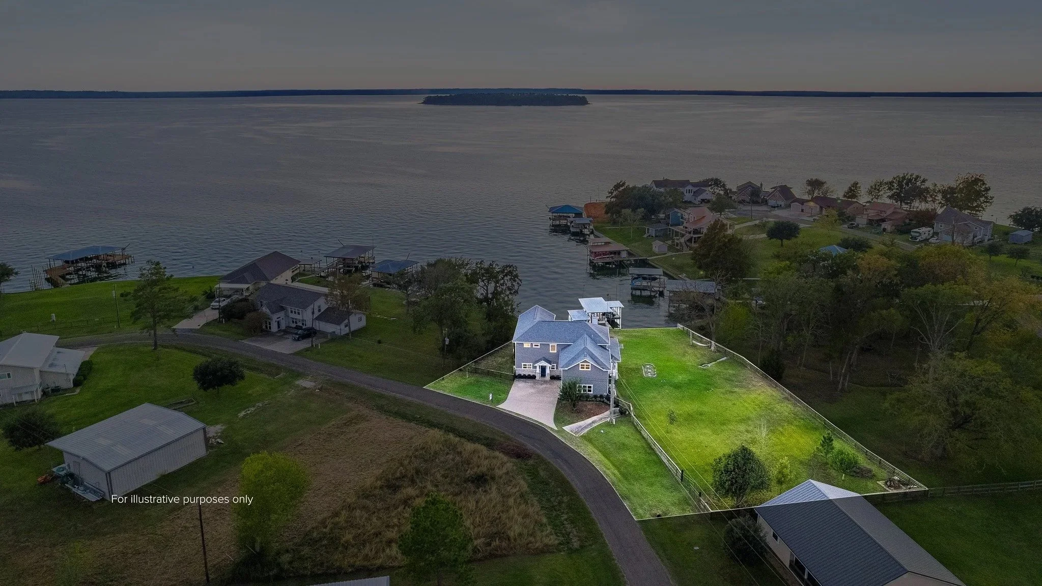 A house with a blue roof next to a large grassy yard, situated by a body of water withdock structures and neighboring houses in the background.