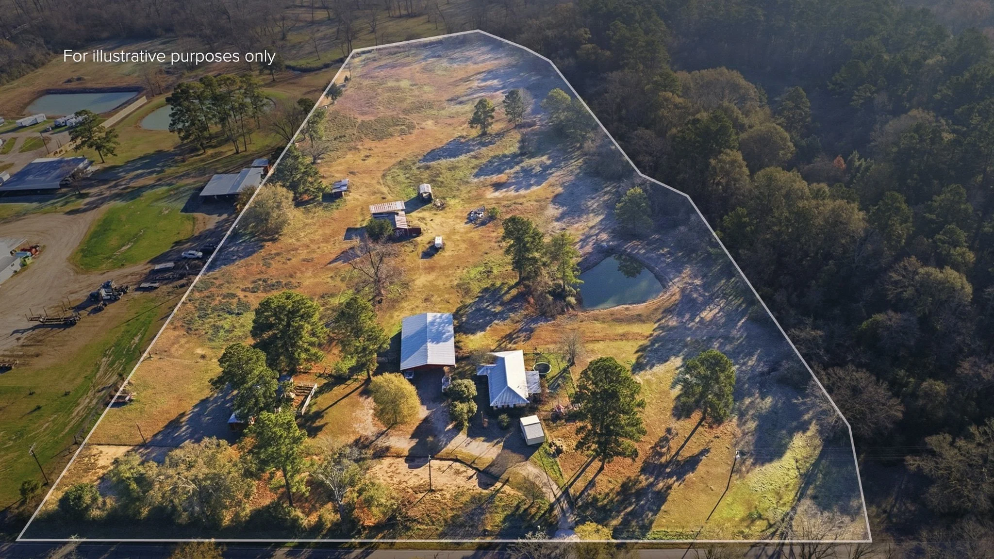 Aerial view of a rural property with multiple buildings, a pond, trees, and open fields, partially outlined with a white boundary line.
