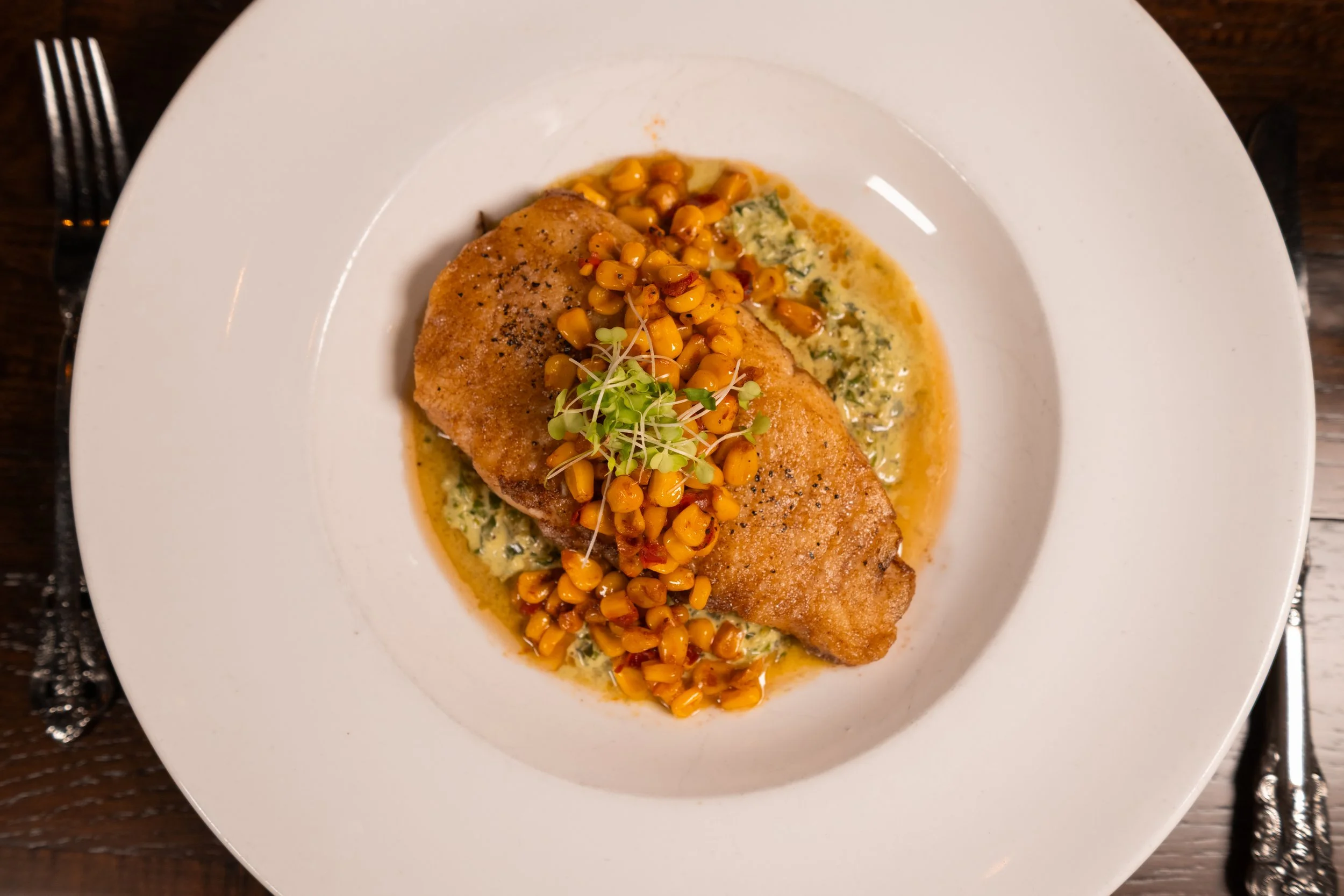 A fish entrée with herb sauce and seasonal garnish at The Hemingway Steakhouse.