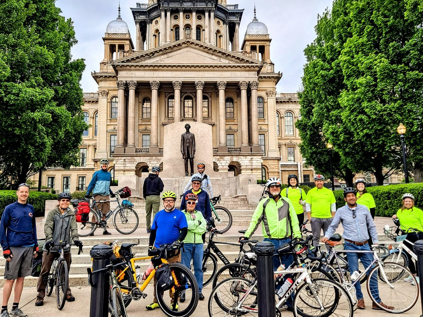 Group of people with bicycles in front of the Illinois state capitol building.