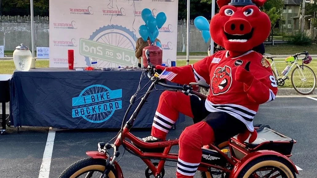 IceHogs mascot, Hammy Hog, giving the camera a thumbs up while riding a ride tricycle.