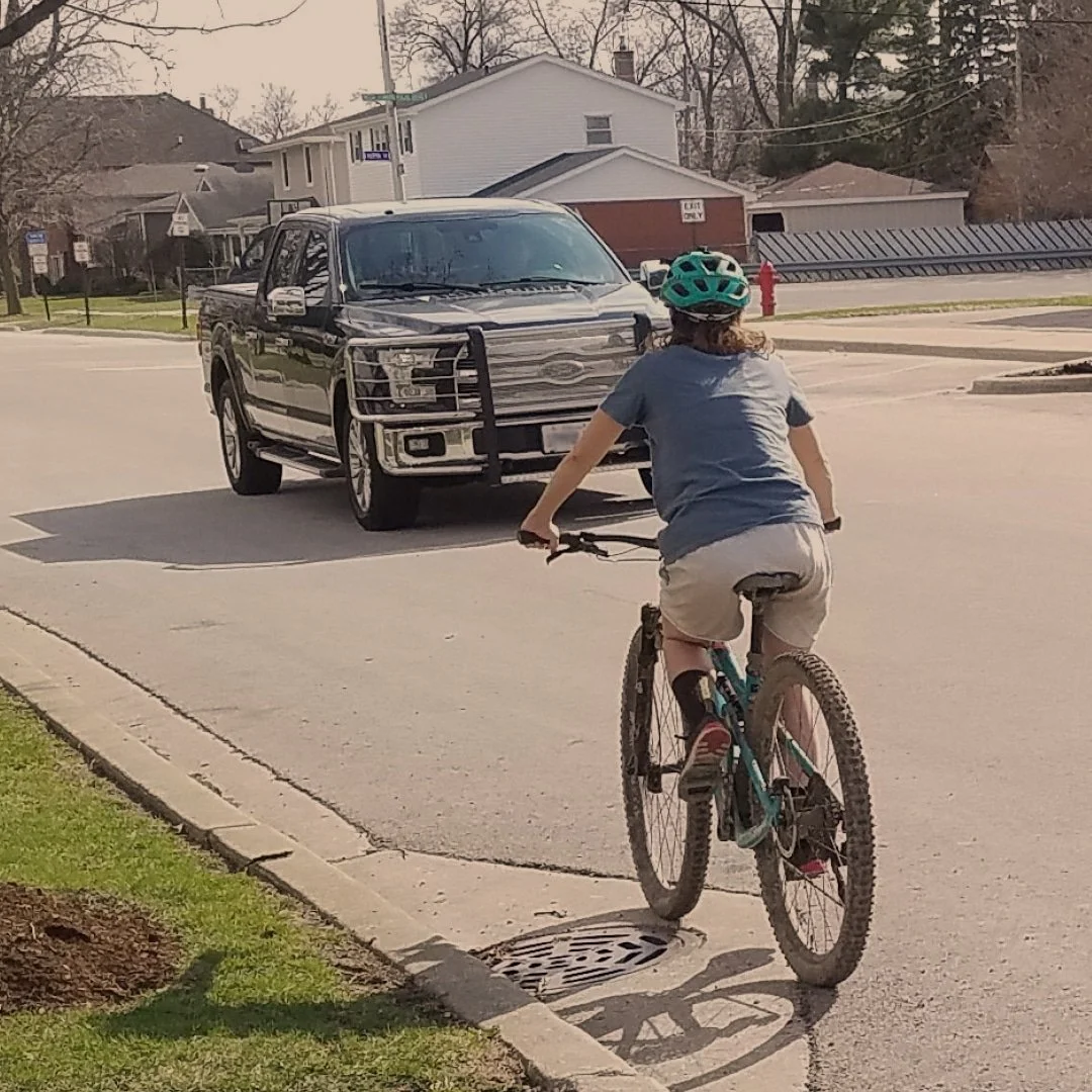 Bicyclist seen riding on the left side of the road, approaching a black pick up truck