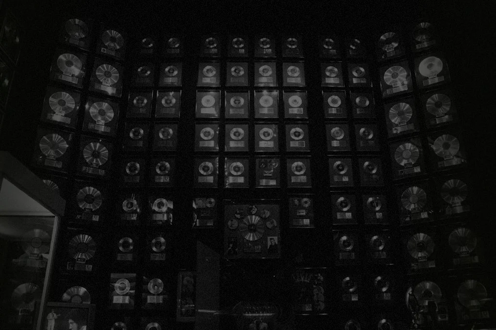 Wall filled with numerous gold and platinum records displayed in a grid pattern.