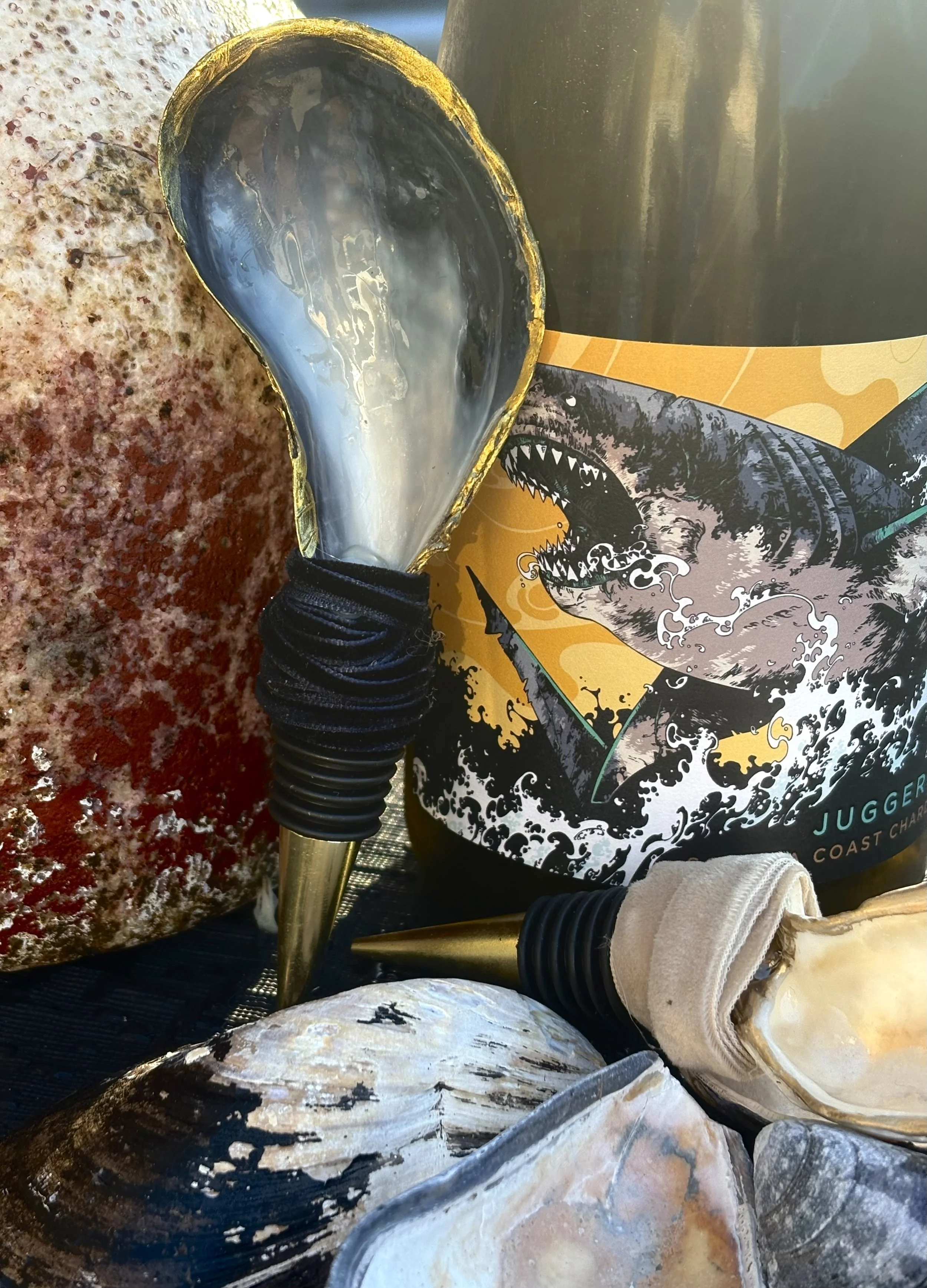 Decorative items including a clam shell, a shell with black markings, a large rock, and two decorative light bulbs, with a background of a poster featuring a dinosaur and ocean waves.