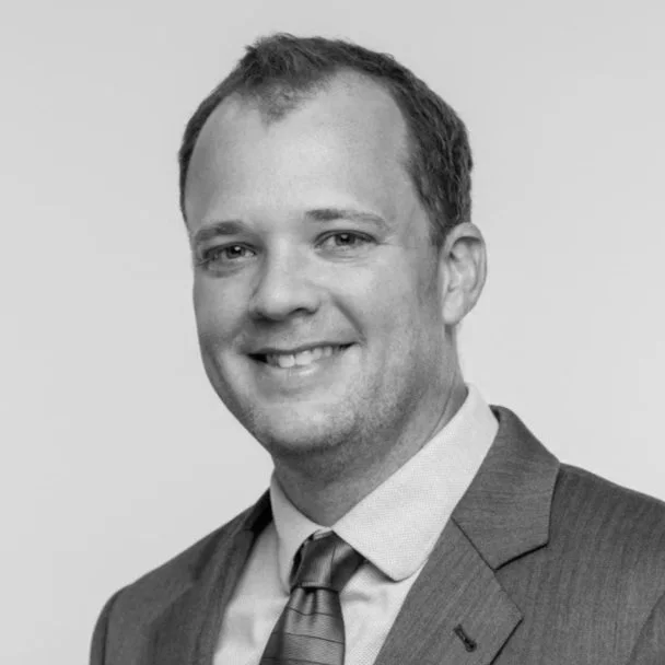 Black-and-white portrait of a smiling man with short hair wearing a suit and tie.