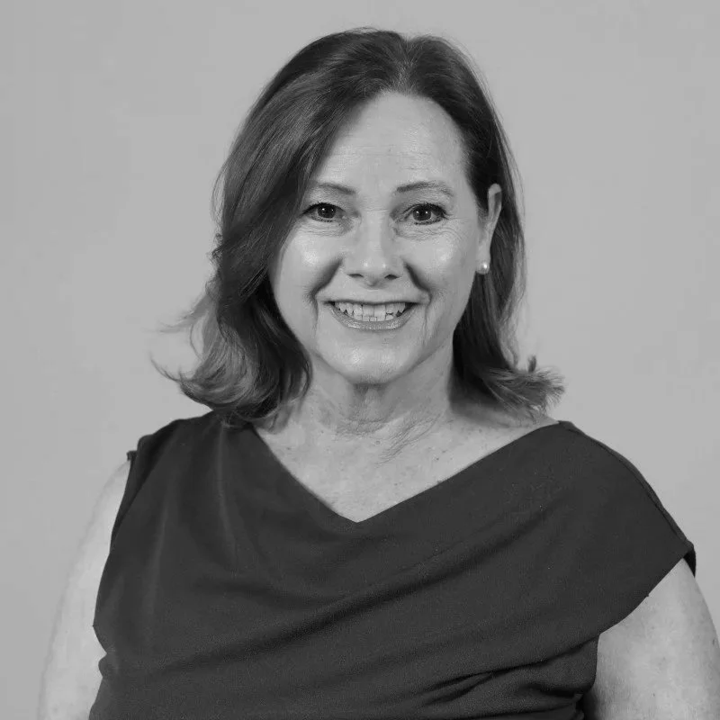 Black and white portrait of a smiling woman with shoulder-length hair, wearing a sleeveless top.