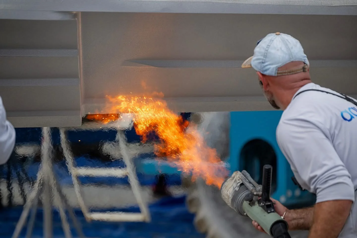 AquaPhobix application with flame shoots polymer powder onto boat bottom surface for long-lasting protection.