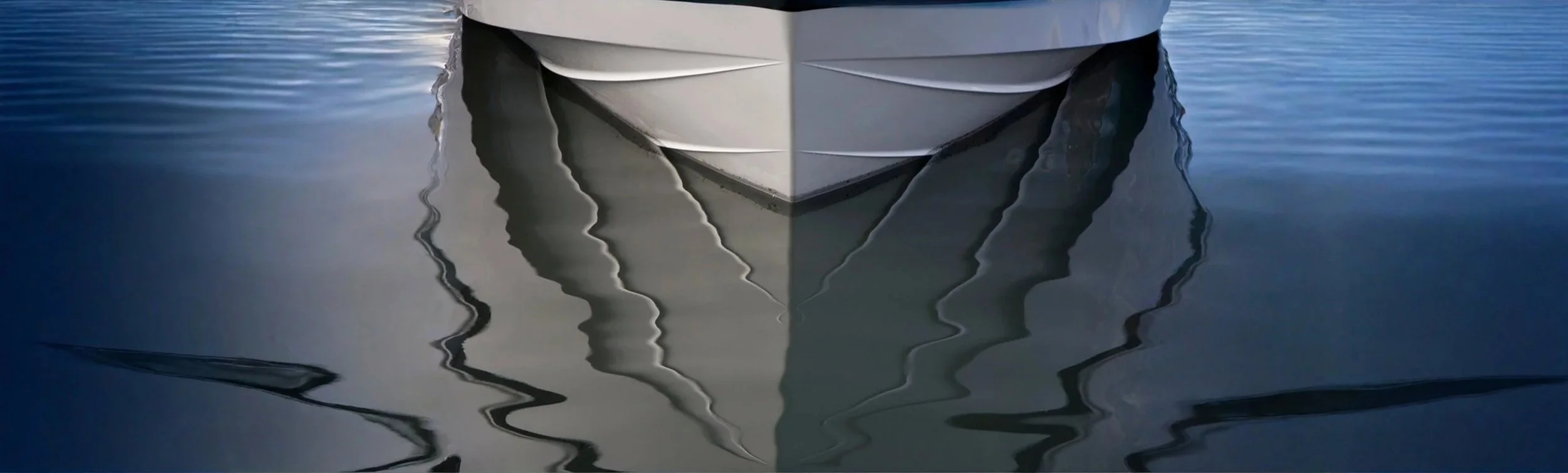 Close-up of the front of a large white boat with reflections in the water.