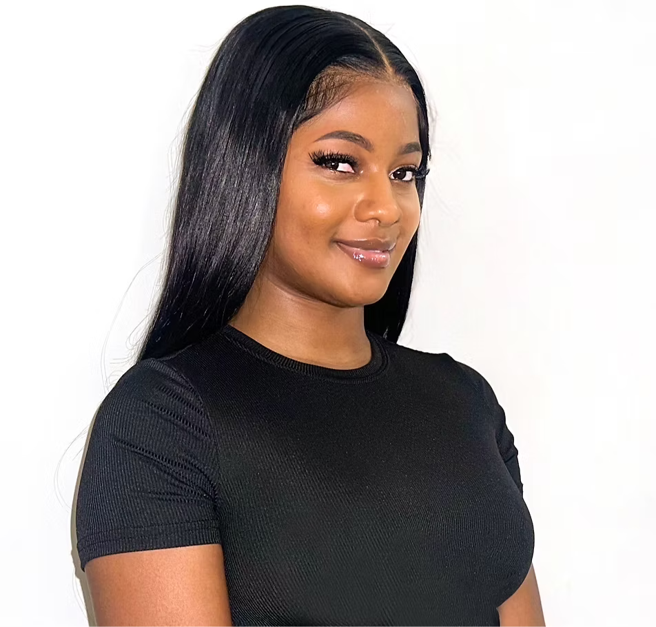 A young woman with straight black hair, wearing a black top, smiling and standing against a white background.