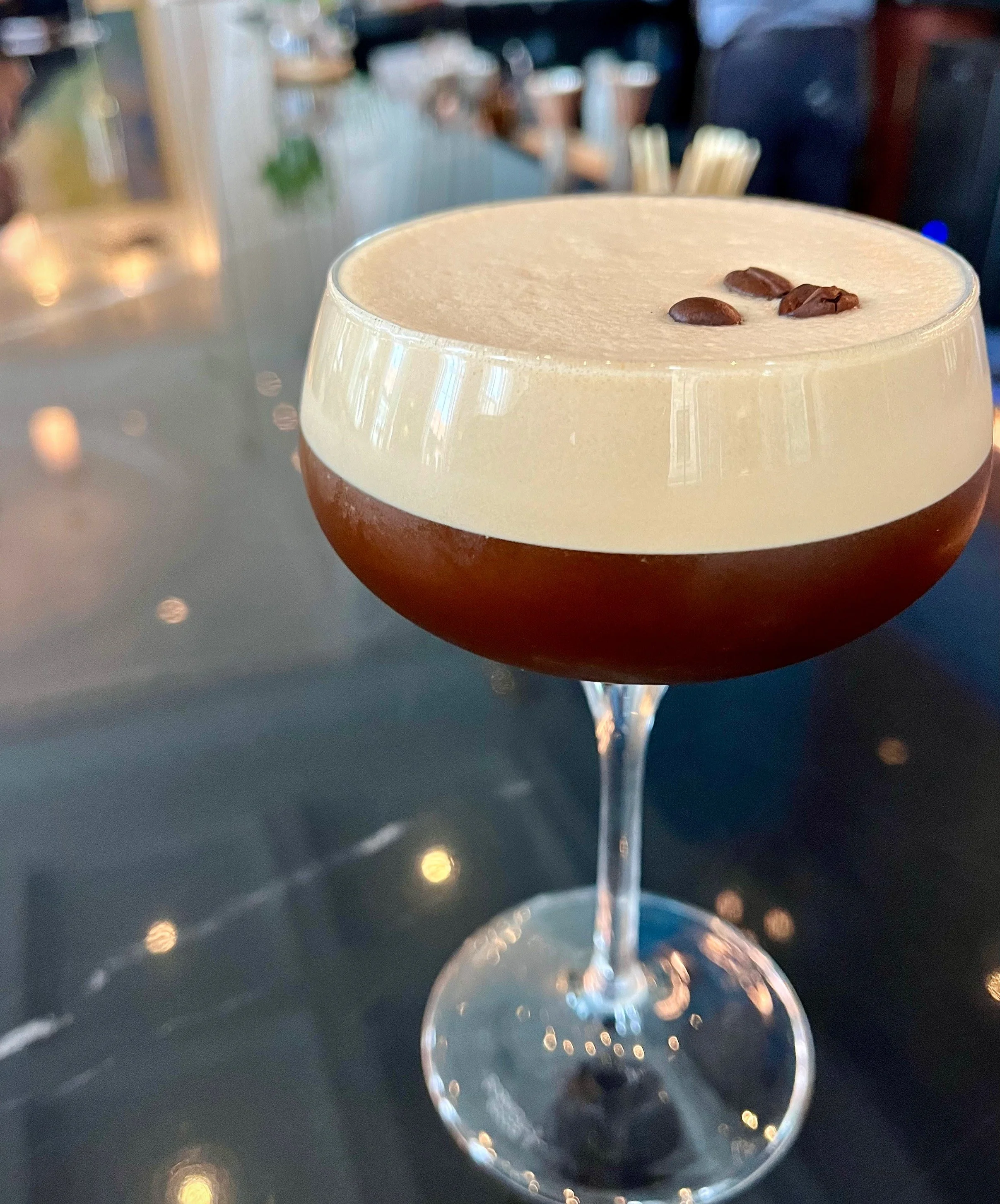 A cocktail in a coupe glass garnished with coffee beans.