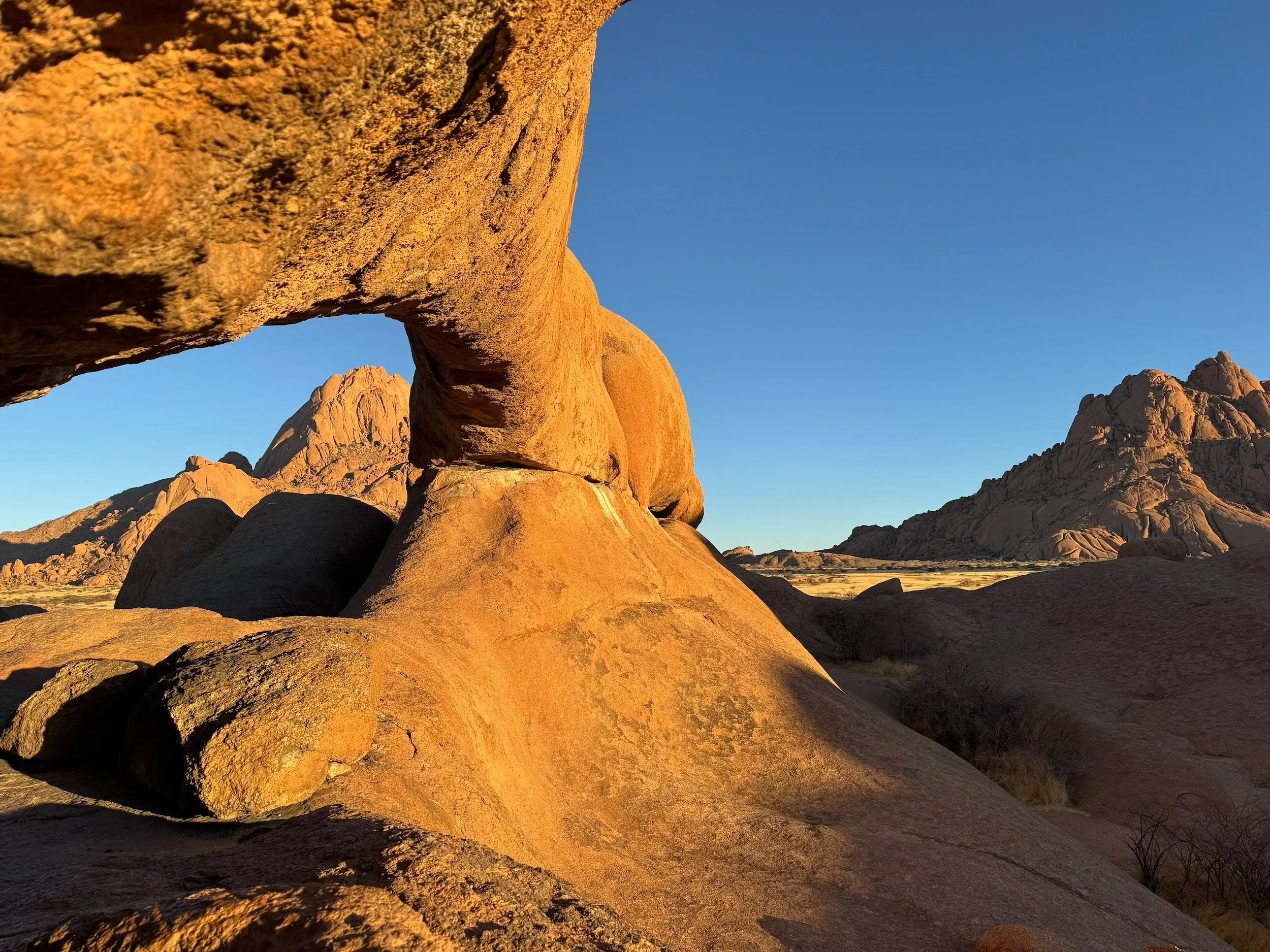 A natural granite rock arch glowing in golden light at Spitzkoppe, Namibia.